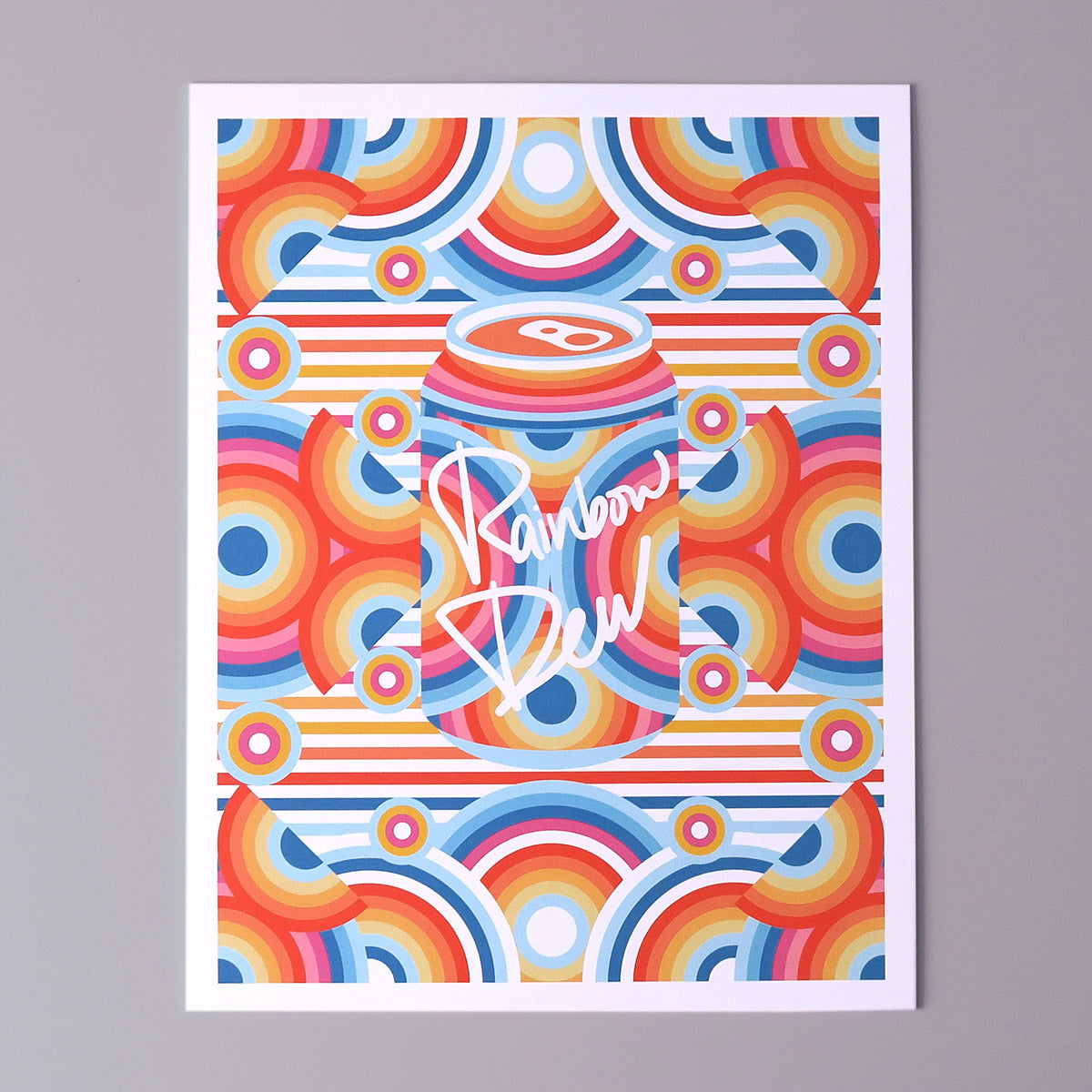 Rainbow Dew is a pop art print that has a multitude of colours. Red, blue, yellow, magenta, sun flower yellow. There are concentric circles that are arranged in a radial way with a drink can in the centre.