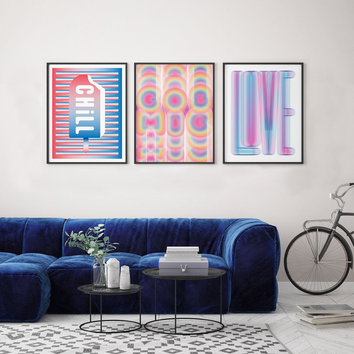 A room with a velvet blue couch and three frames with graphic modern art on display