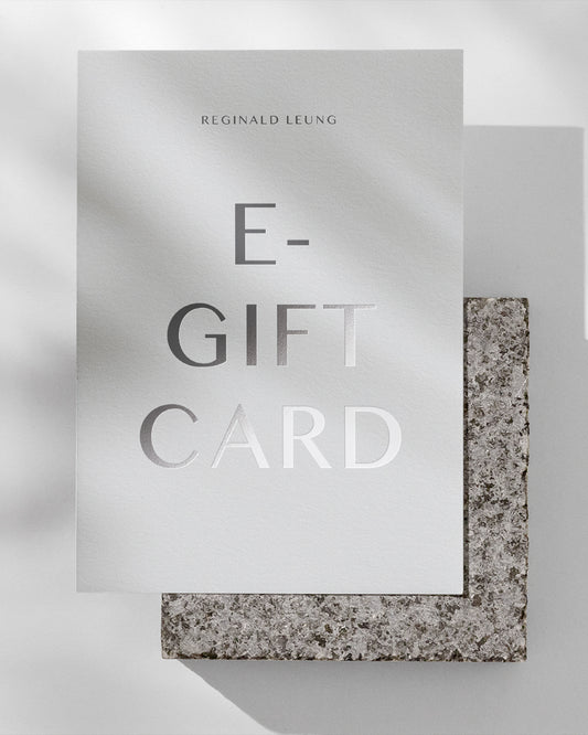 A piece of paper on a grey stone brick with the words E-Gift Card written in metallic foil.