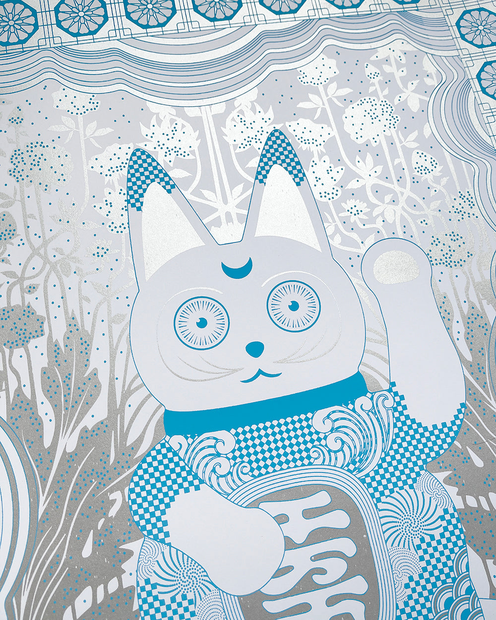 Close up of a lucky cat figure with chinoiserie elements done in metallic silver and cobalt blue.