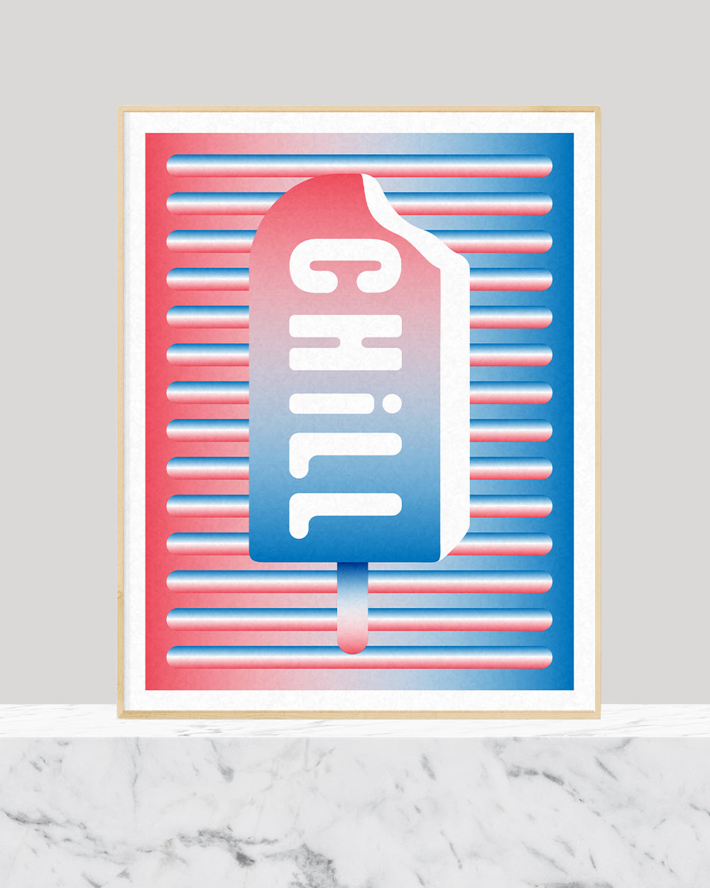 Graphic blue and red popsicle with the word chill in white framed in a picture frame sitting on white marble